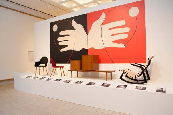 black and red tapestry with two hands hangs on wall above furniture