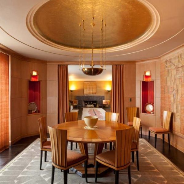 circular wood dining table with chairs beneath convex ceiling