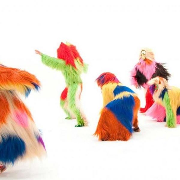 figures in colorful furs pose against white backdrop