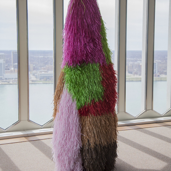 figure in colorful fabrics standing near windows