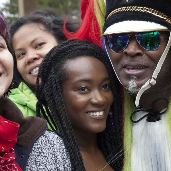 man in fur helmet poses with group of women