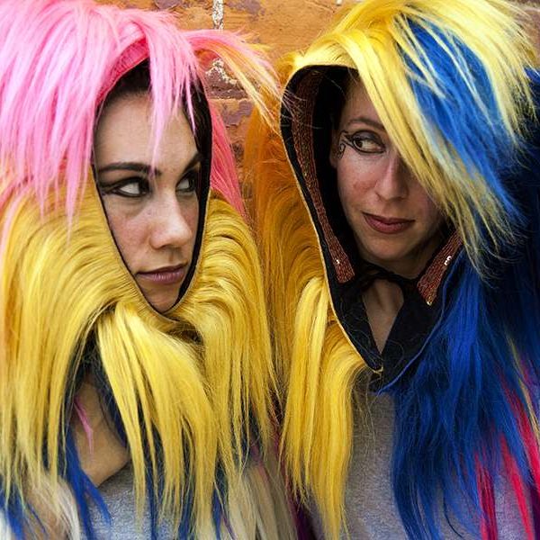 two women wearing colorful manes look at each other