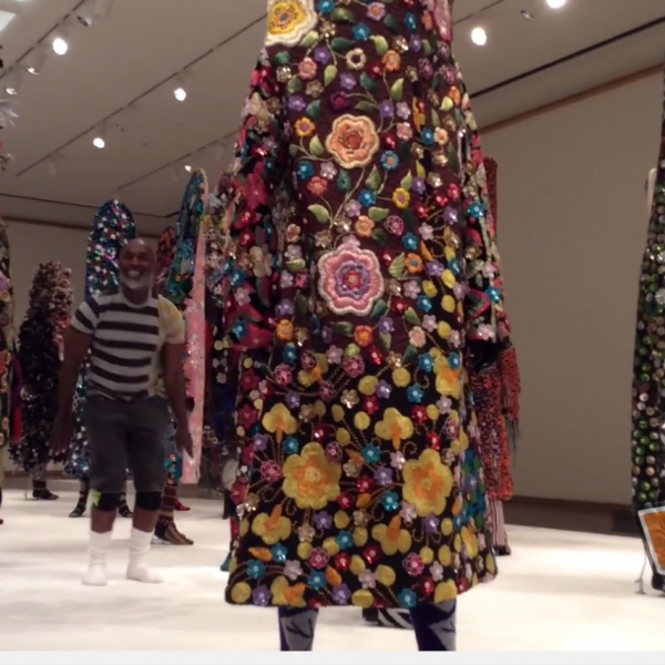 man in striped shirt smiles next to colorful sculptures (2)