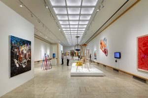 long shot of exhibit hall with painting and wooden sculptures