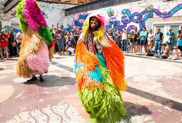 woman dressed in colorful fabric dances in front of crowd