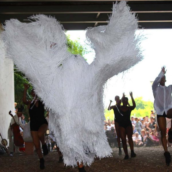 Figure dancing in white, tasseled costume