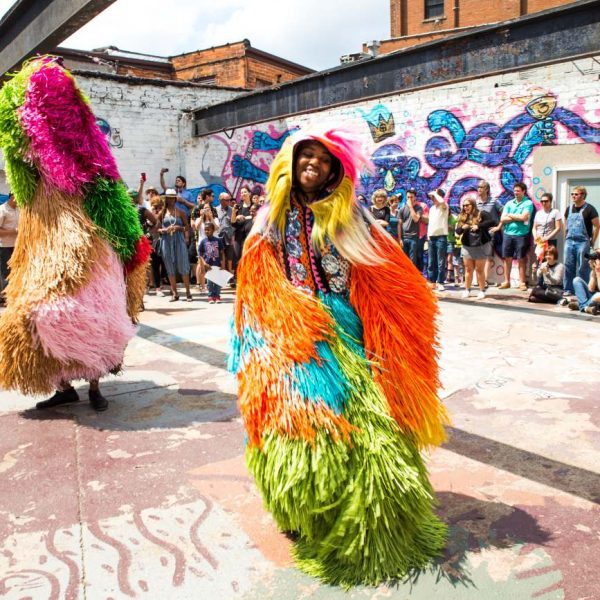 woman dressed in colorful fabric dances in front of crowd