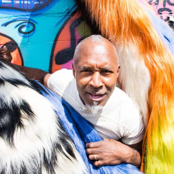 man peeks out from behind colorful furs