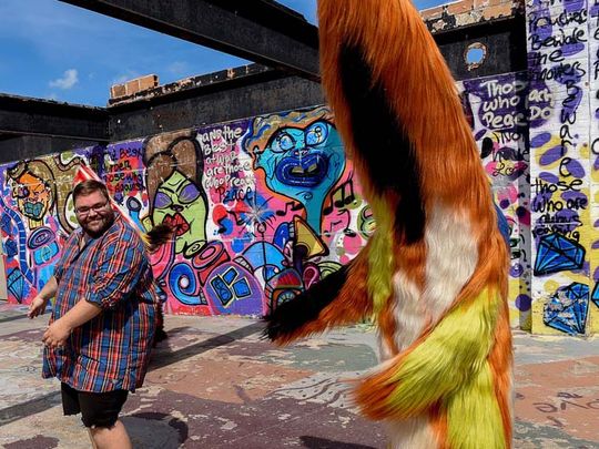 man stands next to dancing figure in fur