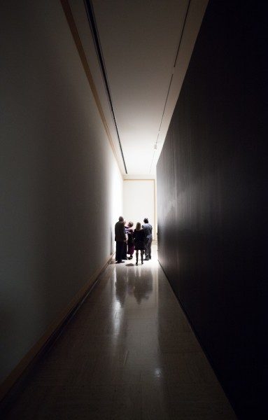 group of people stand at one end of dark hallway