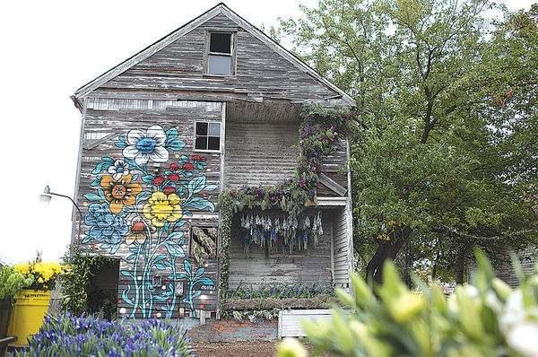 gray wooden house with painted flowers and lilac