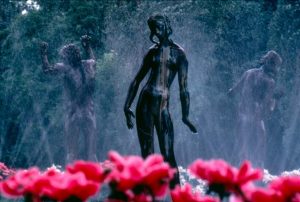 sculpture of woman next to pink flowers