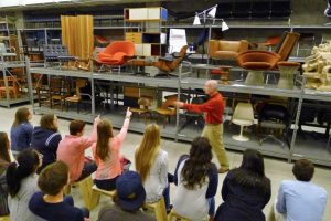 students gesture to chair on storage shelf