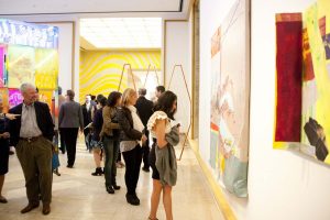 group of people look at hanging artwork