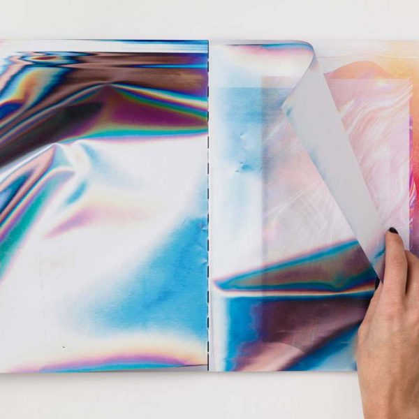 hands flip through pages of reflective paper