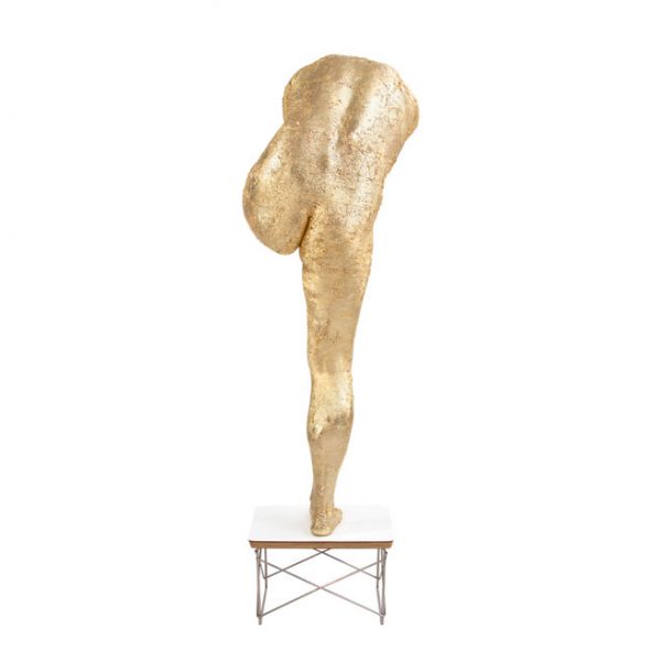 gold sculpture of figure standing on one leg