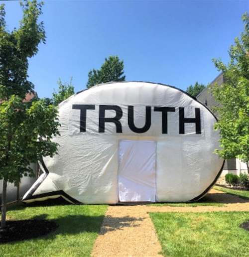 large inflatable speech bubble truth booth sits on lawn