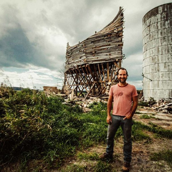 Scott Hocking stands in front of dilapidated wood structure