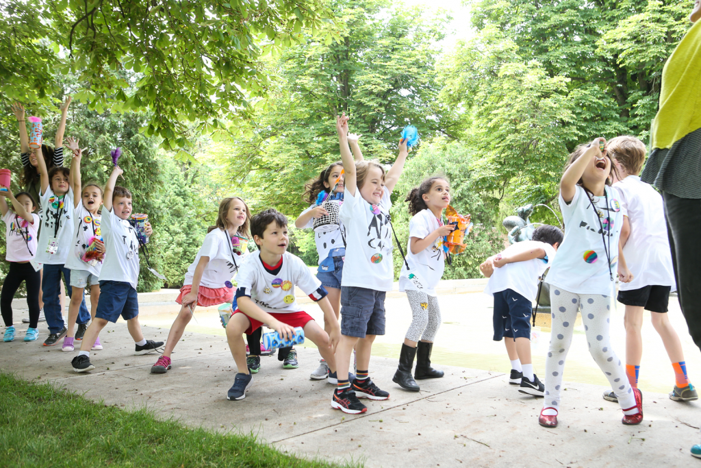 Children cheer while standing on sidewalk