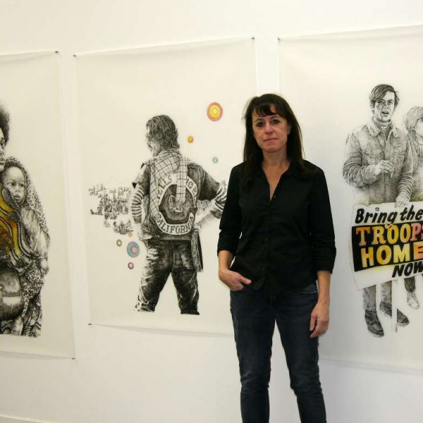 Deborah Aschheim posing with drawings of people
