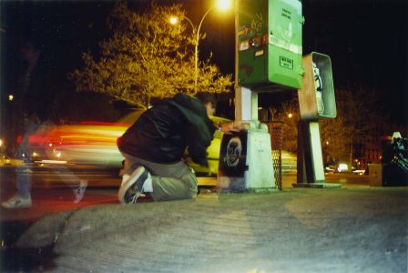 Adam Wallacavage kneels next to phone booth