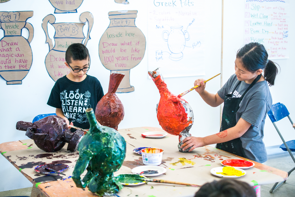 Children painting paper mache pottery