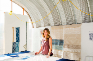 Christy Matson stands in front of blue and brown fabrics