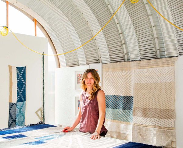 Christy Matson stands in front of blue and brown fabrics