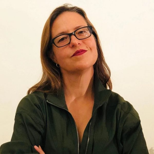 Headshot portrait of woman with brown hair and green jacket with arms crossed